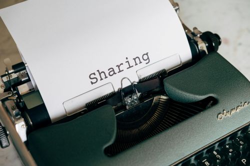 Typewriter with the word "Sharing" on the page - OA Members are encouraged to share